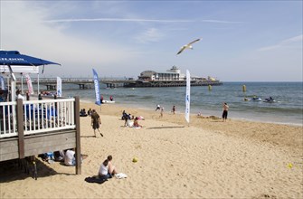 ENGLAND, Dorset, Bournemouth, Tourists playing in the sand and watching speedboat races off the