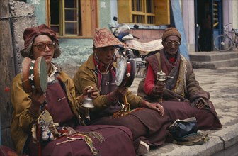 CHINA, Tibet, Lhasa, Monk musicians sat playing in the Barkhor Bazaar.