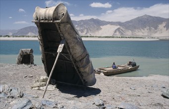 CHINA, Tibet, "Near Tsetang. Yak skin boats, one propped up by a paddle, and a local ferry beside
