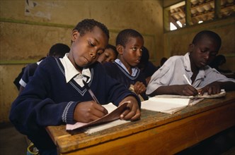 KENYA, Nairobi, Schoolchildren working at desks in classroom.