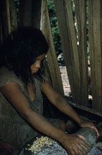 COLOMBIA, Sierra de Perija, Yuko - Motilon, Woman grinds maize using ancient granite mortar and