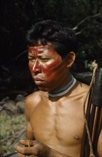 COLOMBIA, Vaupes Region, Tukano Tribe, "Hunter with red “karajuru” / facial paint, wooden ear plug
