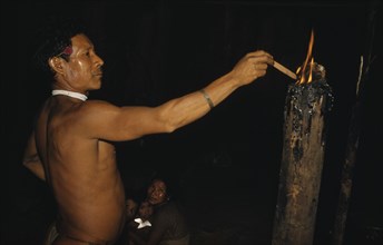 COLOMBIA, Vaupes Region, Tukano Tribe, Headman lights a “breo” resinous torch in centre of the