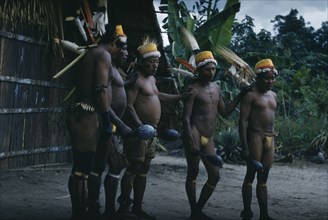 COLOMBIA, Vaupes Region, Tukano Tribe, "Men perform the Maraca Dance outside “maloca” wearing