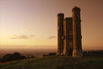 ENGLAND, Worcestershire , Broadway Tower seen in golden light with people standing on grass in the