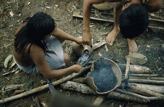 COLOMBIA, Choco Region, Noanama Tribe, Woman pouring “breo” / melted beeswax into a fired “cantaro”