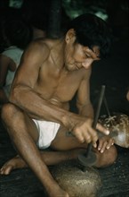 COLOMBIA, Choco Region, Noanama Tribe, Man drills holes in a gourd to make a colander for straining
