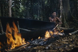 COLOMBIA, Vaupes Region, Tukano Tribe, Man warps open and stretches the sides of the canoe with