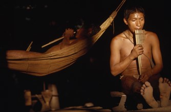 COLOMBIA, Vaupes Region, Tukano Tribe, "Boys playing panpipes at dusk in entrance to maloca /