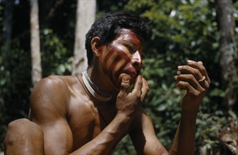 COLOMBIA, Vaupes Region, Tukano Tribe, Man applies “karajuru” / facial paint before he goes hunting