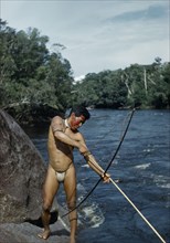 COLOMBIA, Vaupes Region, Tukano Tribe, Man fishing with “macana” wood bow and bamboo arrow in rio