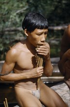 COLOMBIA, Vaupes Region, Tukano Tribe, Boy playing the “carizu” / panpipes at the maloca’s river