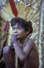 COLOMBIA, Vaupes Region, Tukano Tribe, Young boy playing panpipes outside maloca prior to a