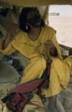 COLOMBIA, Guajira Peninsula, Guajiro / Wayuu Tribe, "Woman embroiders a “faja” / woven woollen belt