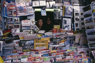 ITALY, Campania, Naples, Two women looking out from newsagents stall completely surrounded by
