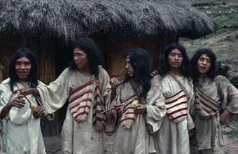 COLOMBIA, Indigenous Tribes, Kogi, Chendukua. A group of Kogi men outside a grass-thatched village