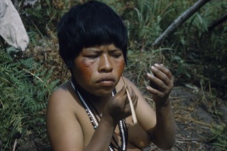 COLOMBIA, Sierra de Perija, Yuko - Motilon , Girl applying bright red “Achiote” facial paint