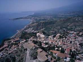 ITALY, Sicily, Messina, View South over the rooftops of  the town of Taormina to Giardini Naxos.