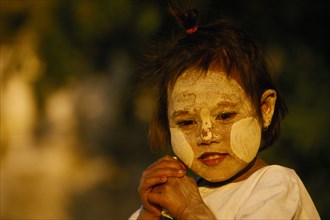MYANMAR, Pagan, "A young girl near Bupaya Pagoda, with white painted face, circles on her cheeks."