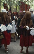 CHINA, Xinjiang, Kashgar, Veiled women selling hats amongst the crowd at the Sunday Market.