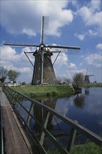 HOLLAND, Zuid Holland, Kinderdijk, Windmill seen from across a narrow footbridge over water