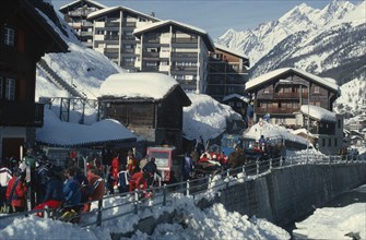 SWITZERLAND, Valais, Zermatt, Crowded ski resort in snow with mountain backdrop.