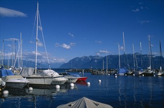 SWITZERLAND, Vaud, Lutry, Boats moored in marina with view across Lake Geneva beyond.
