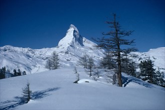 SWITZERLAND, Valais, Looking across snow covered landscape towards peak of the Matterhorn.