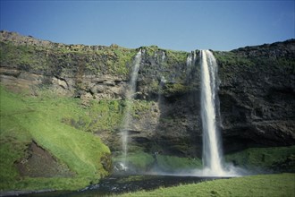 ICELAND, South Coast, Waterfall plummeting over cliff by the south coast ring road near Skogar.