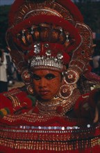 INDIA, Kerala, Thrissur, "Theyyam dancer in a red costume and painted face, at The Great Elephant