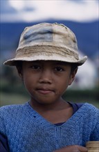 MADAGASCAR, People, children, Road to Ambositra. Portrait of a young boy wearing a dirty hat and
