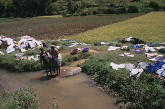 MADAGASCAR, Work, Near Ambositra. Women doing laundry in a river with the clothes left to dry in