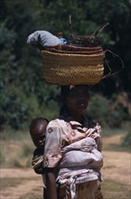 MADAGASCAR, People, Women , Near Ambositra. Portrait of a woman carrying a baby in a sling on her