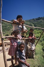 MADAGASCAR, People, Near Ambositra. Rural family leaning on make shift wooden fence