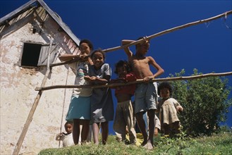 MADAGASCAR, People, Near Ambositra. Rural family leaning on make shift wooden fence