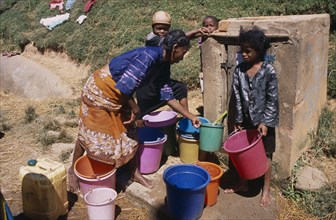 MADAGASCAR, Ambositra, A woman with children collecting water from a nearby public supply point