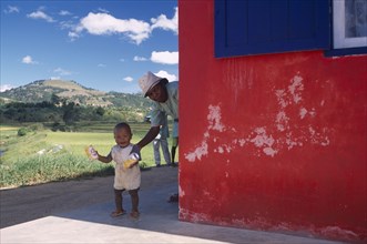 MADAGASCAR, People, Road to Fianarantsoa. Toddler with Grandmother appearing from around exterior