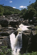 MADAGASCAR, Ranomanfana National Park, Waterfalls cascading over rocks surrounded by lush green