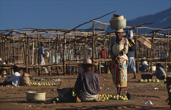 MADAGASCAR, Ambalavao, Two women selling fruit at a sunday market place with empty stalls one woman