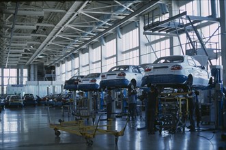 UKRAINE, Zaporozhye, Cars raised off the ground with staff working underneath in a production