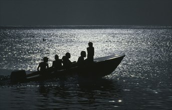 JAMAICA, Transport, People traveling on a motorboat at night silhouetted against the light of the