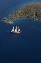 WEST INDIES, US Virgin Islands, St Thomas, Elevated view over sailing boat passing rocky projectory