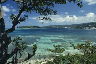 WEST INDIES, Jamaica, Port Antonio, View across turquoise sea towards beach and tree covered coast