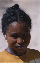 MADAGASCAR, Tulear, Ifaty Beach. Head and shoulders portrait of a young girl wearing mud mask on