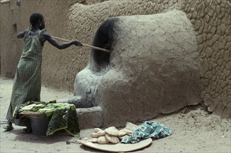 MALI, Timbuctu, "Woman making bread, cooking outside using mud brick oven."