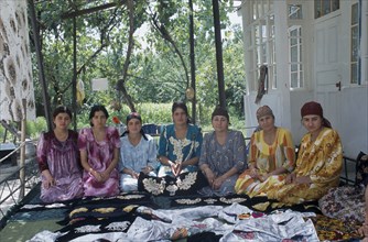 TAJIKISTAN, People, Seven sisters sat in a row with fabric layed out in front of them.