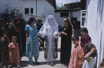 TAJIKISTAN, Wedding, "The bride wearing a veil and highly decorated jacket, surrounded by guests at
