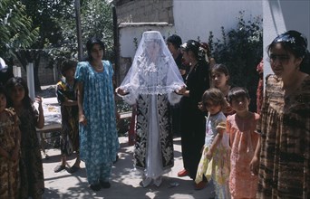 TAJIKISTAN, Wedding, "The bride in a white dress, veil and decorated jacket surrounded by guests at
