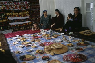 TAJIKISTAN, Food, "Three women and two children sit by a large display of food laid out, awaiting