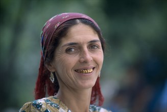 TAJIKISTAN, People, "Portrait of a woman with a dark red head scarf, earrings and gold teeth"